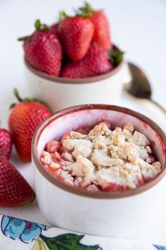 two bowls filled with oatmeal and strawberries on top of a table