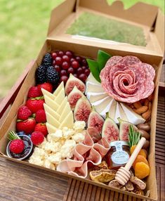 a box filled with assorted meats and fruit on top of a wooden table