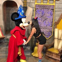 a woman in a mickey mouse costume is touching a man's face