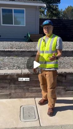 a man wearing a safety vest standing in front of a house