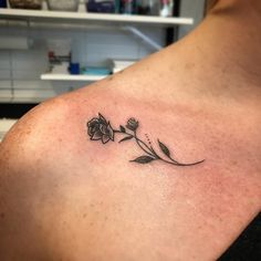 a woman's shoulder with a small flower tattoo on the left side of her chest