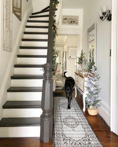 a black dog is walking down the stairs in a house with christmas decorations on it