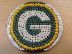 a cake with the letter g on it is decorated in green, yellow and white