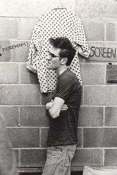 a young man leaning against a brick wall