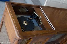 an old record player is sitting on top of a wooden cabinet with its lid open