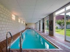 an indoor swimming pool surrounded by brick walls and glass doors leading to the back yard