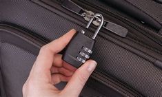 a person holding a lock on top of a piece of luggage