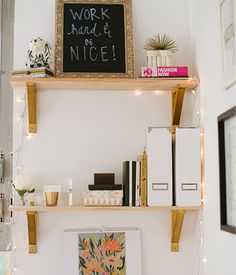 a desk with some books on top of it and a chalkboard above the shelves