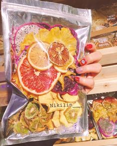 a person holding up a bag filled with sliced oranges and kiwi fruit slices