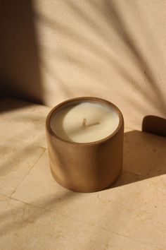 a lit candle sitting on top of a table next to a shadow from the wall