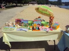 a table with books and an umbrella on the beach