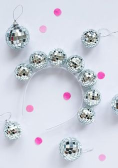 silver disco ball ornaments on a white surface with pink polka dotes in the background