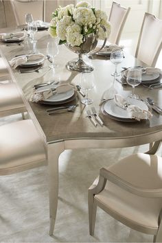 a dining room table set with silverware and white flowers