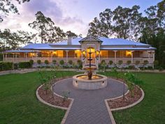 a large house with a fountain in the middle of it's front yard at dusk