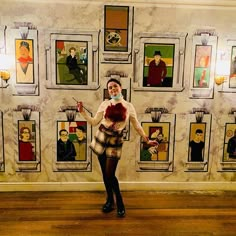 a woman standing in front of a wall with pictures on it