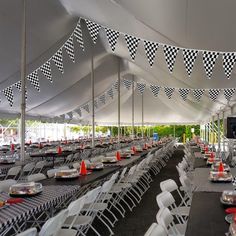 tables and chairs are set up in a tent for an event or party with black and white checkered flags