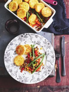 a white plate topped with fried food next to a bowl of green beans and corn