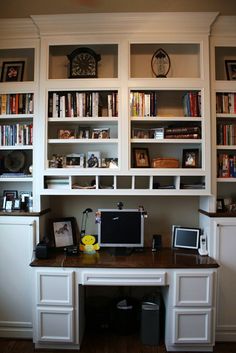 a desk with a computer on top of it in front of some bookshelves