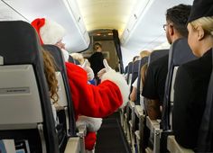 a man dressed as santa clause sitting on an airplane with other people in the aisle