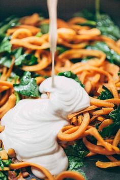 a bowl filled with noodles and sauce being drizzled on top of it