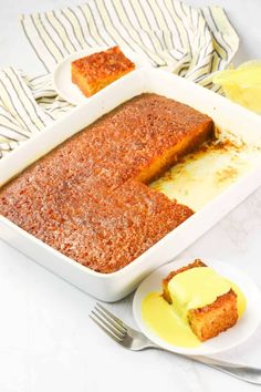 a cake in a white dish with yellow icing on it and two slices of cake next to it