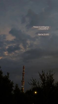 a tall tower sitting under a cloudy sky with a quote on it's side