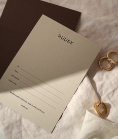 two pairs of gold wedding rings sitting on top of a bed next to an envelope