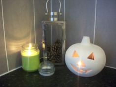 a white pumpkin sitting next to a candle on top of a counter with a lantern in front of it