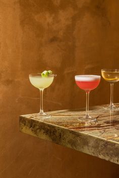 three different colored drinks sitting on top of a table