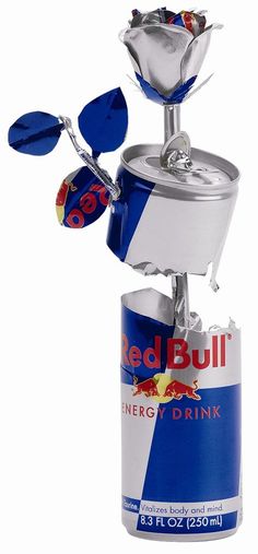 a blue and white can with flowers in it's top is next to a red bull