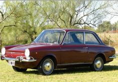 an old car is parked in the grass