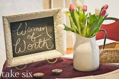 a vase filled with tulips sitting on top of a table next to a chalkboard