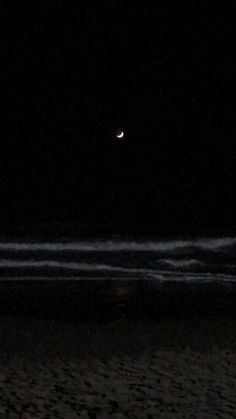 the moon is shining in the dark sky over the beach