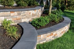 a stone retaining wall in the middle of a grassy area