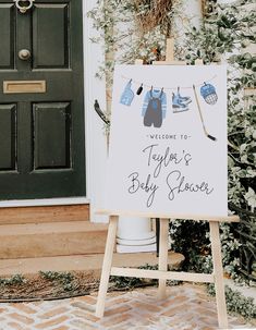 a welcome sign for a baby shower is displayed in front of a door with greenery