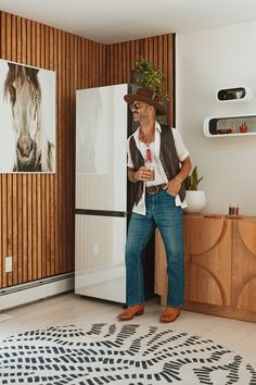 a man wearing a cowboy hat standing in front of a refrigerator freezer with his hand on his hip