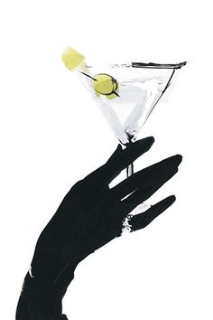 someone holding up a martini glass with a lemon in it