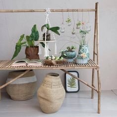 a bamboo shelf with potted plants on it next to other pots and vases