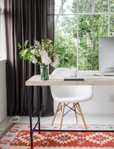 a white desk with a laptop computer on top of it next to a red rug