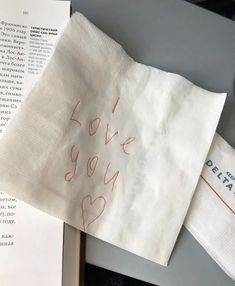 two napkins with i love you written on them sitting next to an open book