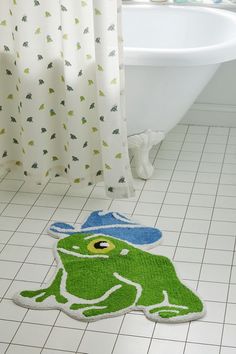 a bathroom with a frog rug on the floor and a bathtub in the background