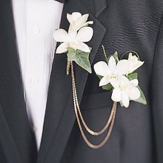 a close up of a person wearing a suit and tie with flowers on the lapel