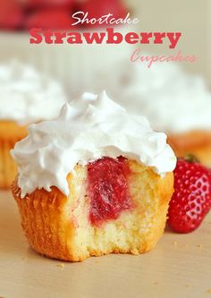 some cupcakes with white frosting and strawberries on top