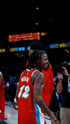 a man with dreadlocks is walking on the court in front of other people