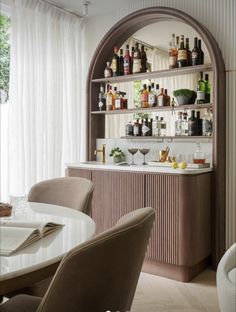 a dining room table and chairs with bottles on the shelves