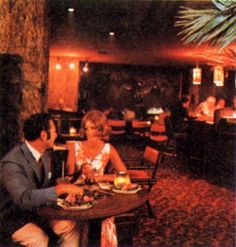 a man and woman sitting at a table in a restaurant with food on the plate