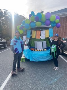 two people standing in front of a car with balloons on it