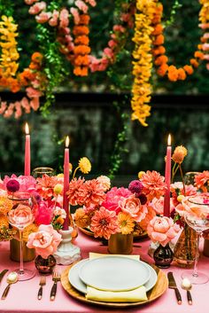 a table set with plates, candles and flowers