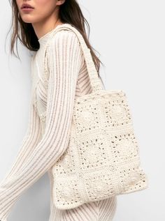 a woman is holding a white crochet bag