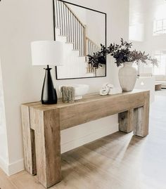 a wooden table with two vases on top of it next to a stair case